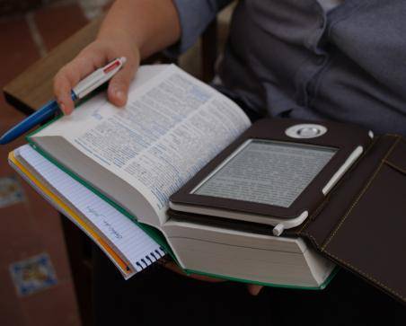 Foto de un libro abierto con un e-book encima