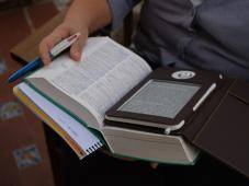 Foto de un libro abierto con un e-book encima